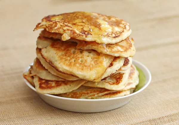 Pancakes with honey on canvas background, close-up — Stock Photo, Image