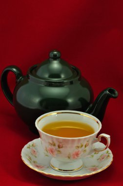 Porselen çay bardağı çay ve yeşil çaydanlık üstünde kırmızı bir backgro dolu