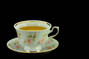 Porselen çay bardağı çay ve yeşil çaydanlık üstünde siyah bir backgr dolu