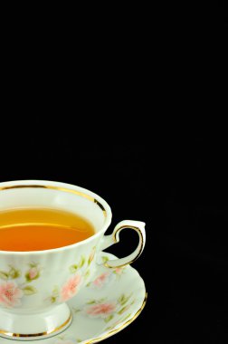 Porselen çay bardağı çay ve yeşil çaydanlık üstünde siyah bir backgr dolu