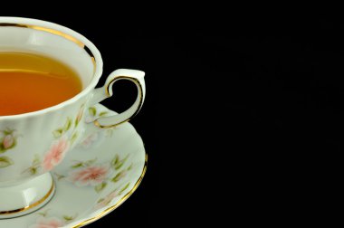 Porselen çay bardağı çay ve yeşil çaydanlık üstünde siyah bir backgr dolu