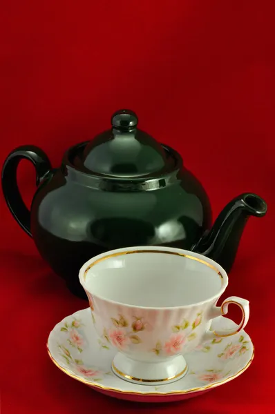Eine Teetasse und eine grüne Teekanne auf rotem Hintergrund — Stockfoto