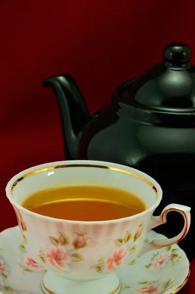 Eine Tasse Tee und eine grüne Teekanne auf rotem Hintergrund — Stockfoto