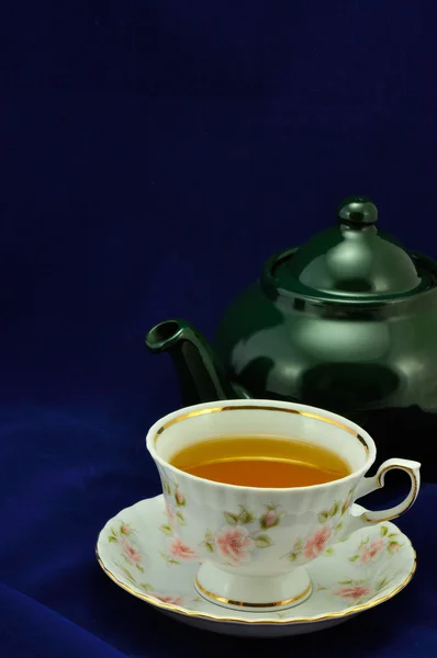Egy csésze tea és zöld teáskanna kék háttérrel — Stock Fotó