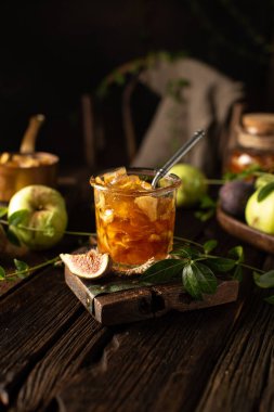 Ev yapımı elma reçeli, ahşap masa üzerinde incir, kırsal tarzda, antika tabaklarla. Karanlık ruh hali..