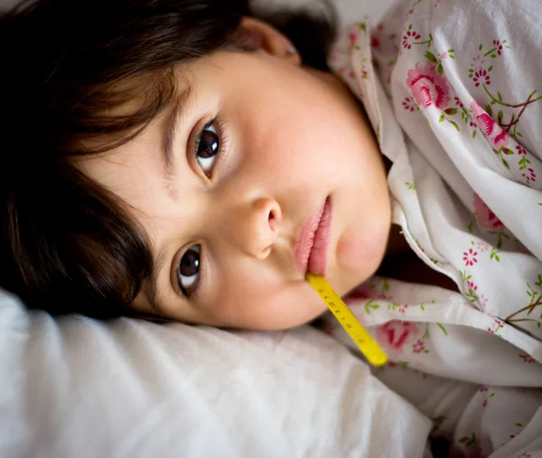 Kleines Mädchen mit Thermometer im Bett — Stockfoto