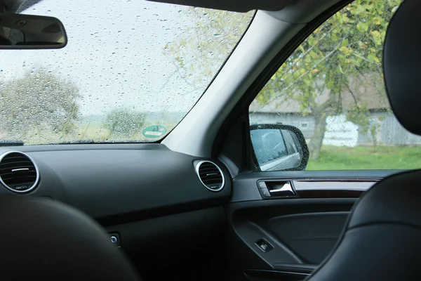 Nascondersi dentro l'auto durante la pioggia battente Immagine Stock