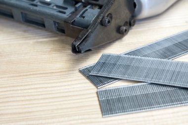 çivi tabancası ve çam ahşap masa üzerinde çivi