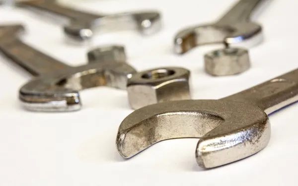 Wrench compasses and nuts on white table background — Stock Photo, Image