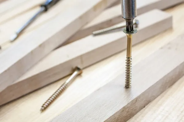Schroeven en schroef-driver op bouw met houten planken achtergrond — Stockfoto