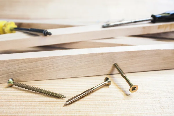 Tornillos y destornillador en construcción con tablones de madera de fondo — Foto de Stock