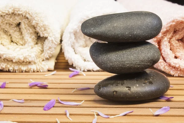 Zen stones with petals and towels on slatted wood background — Stock Photo, Image