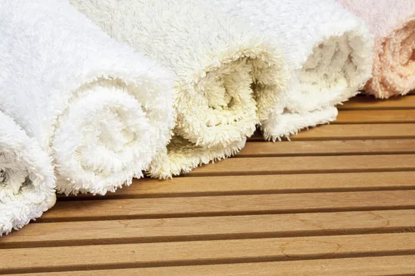 Line of towels with different colours on slatted wood background — Stock Photo, Image