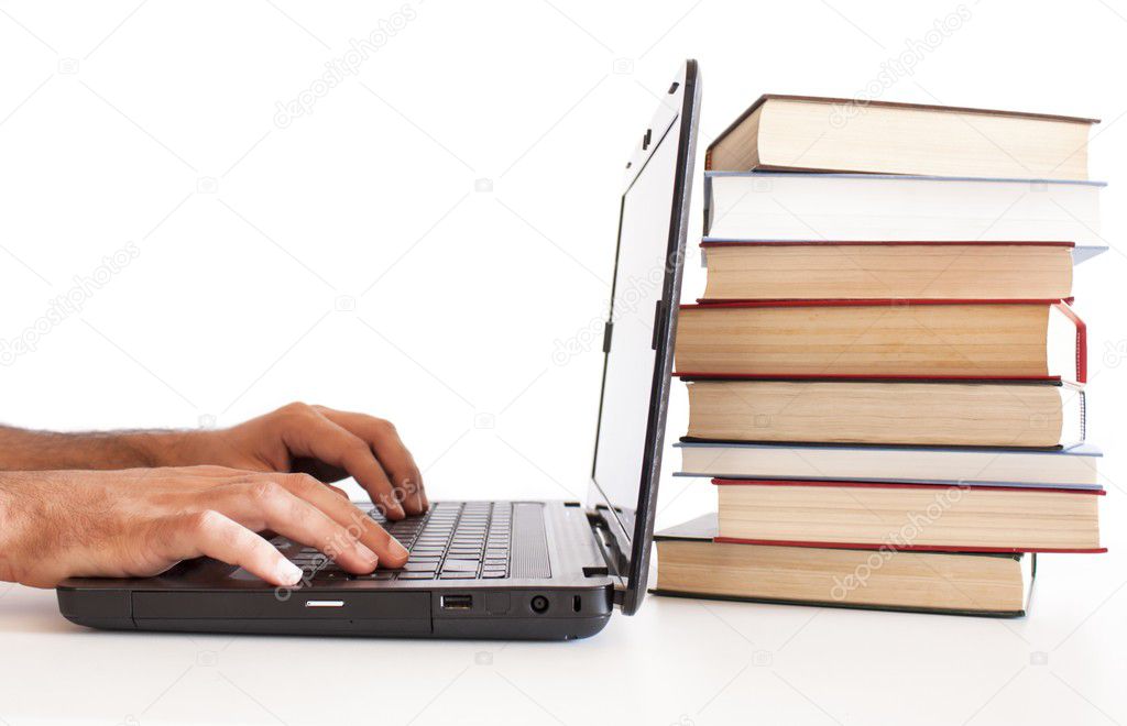 Man working on computer with pile of books back