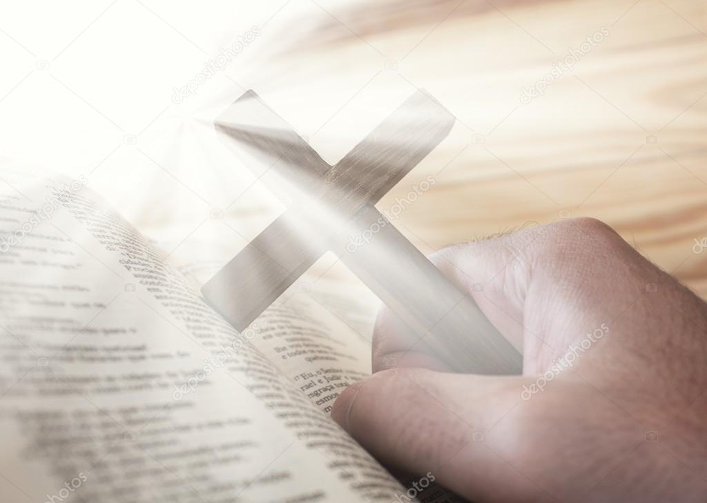 Man holding the cross with bible and divine light