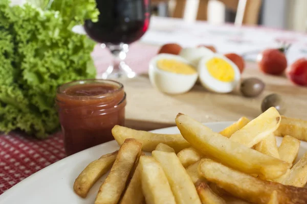 Ranskalaiset perunat ja ketsuppi keittiön pöydällä — kuvapankkivalokuva