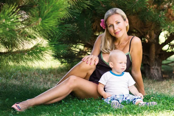 Çimlerde oturan bir çocuk ile güzel bir kadın — Stok fotoğraf