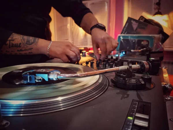 Bir DJ 'in elleri bir dans salonunda müzik plağı çalıyor.