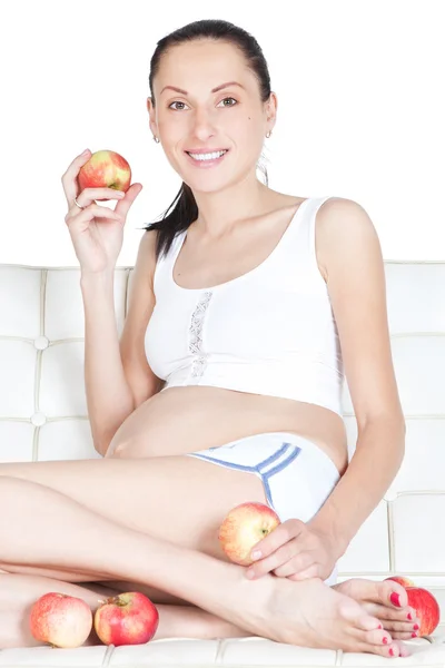 Mujer embarazada joven comiendo manzana roja en el estudio — Foto de Stock