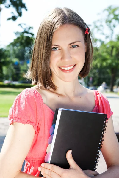 Hermosa chica estudiante con cuaderno sentado al aire libre — Foto de Stock