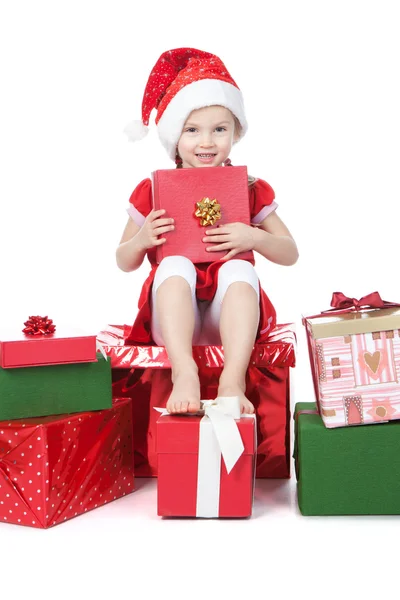 Linda niña en sombrero de ayudante de santa con regalos en blanco — Foto de Stock