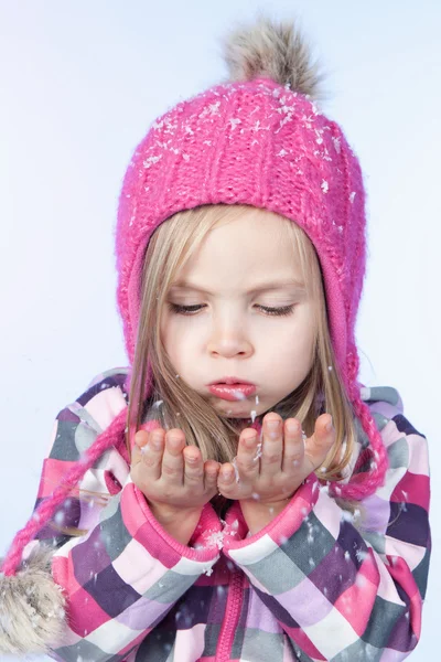 Malá krásná dívka se sněhem v rukou, modré pozadí — Stock fotografie