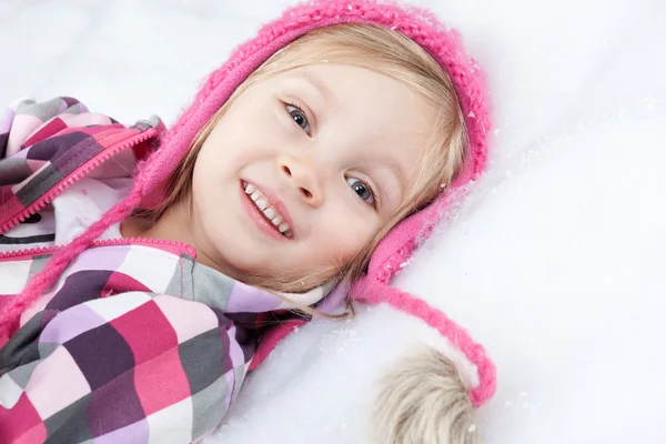 Kar üzerinde yatan küçük mutlu kız portresi — Stok fotoğraf