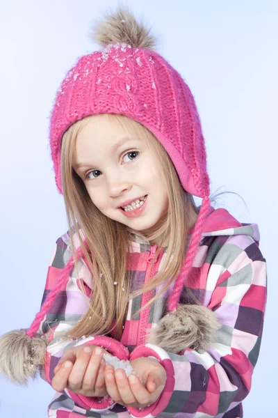 Pequena menina bonita com neve nas mãos, fundo azul — Fotografia de Stock