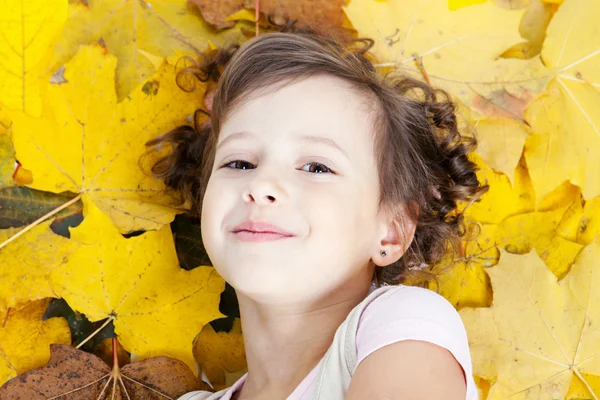 Carino poco sorridente ragazza in autunno foglie — Foto Stock