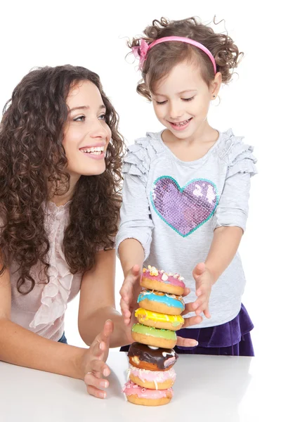 Bild von glücklicher Mutter und kleinem Mädchen mit bunten Donuts — Stockfoto