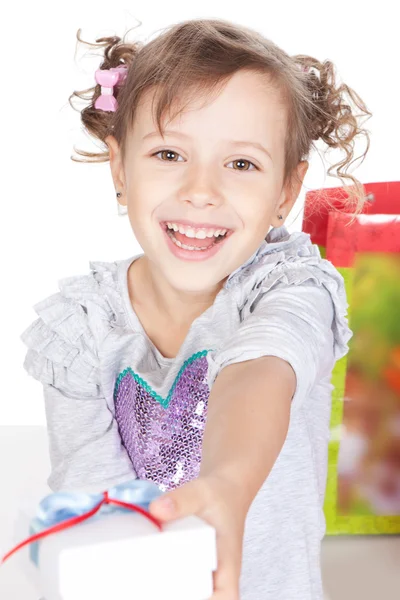 Glücklich lächelndes kleines Mädchen, das dir im Studio ein Geschenk macht — Stockfoto