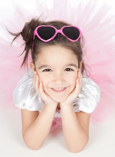 Schöne kleine Mädchen in einem rosa Kleid mit Brille über weiß — Stockfoto