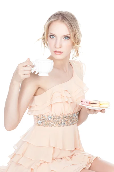 Hermosa joven sosteniendo macarrones y taza de té —  Fotos de Stock