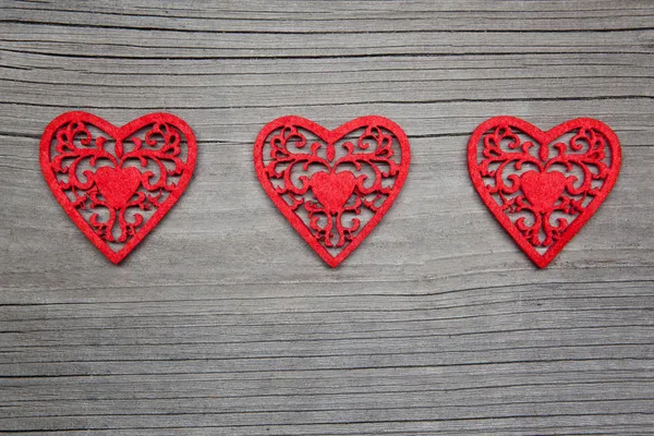 Tři srdce na dřevěné pozadí — Stock fotografie