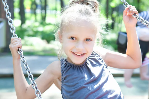Happy little girl on a swing in the park — Stock Photo, Image