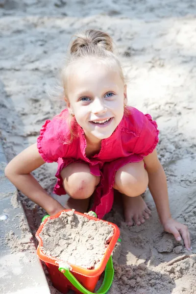 Liten flicka som leker på en sandlåda — Stockfoto