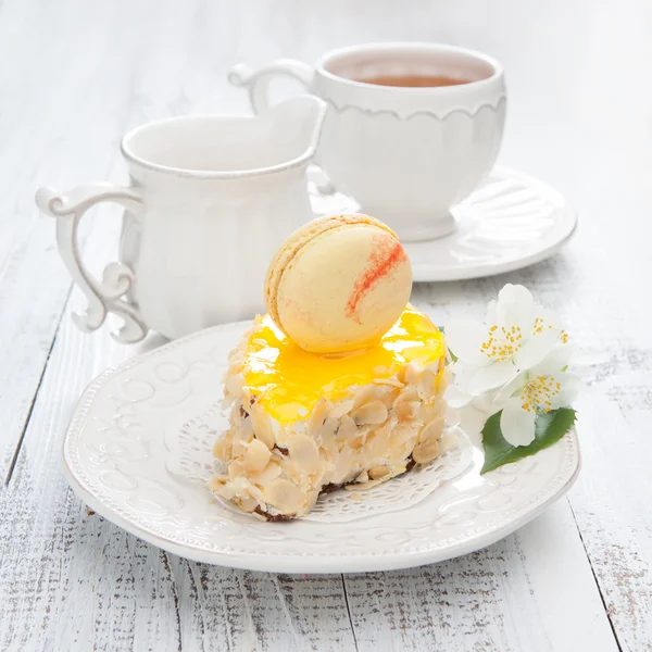 Sweet cake with french macaroons on white wooden table — Stock Photo, Image