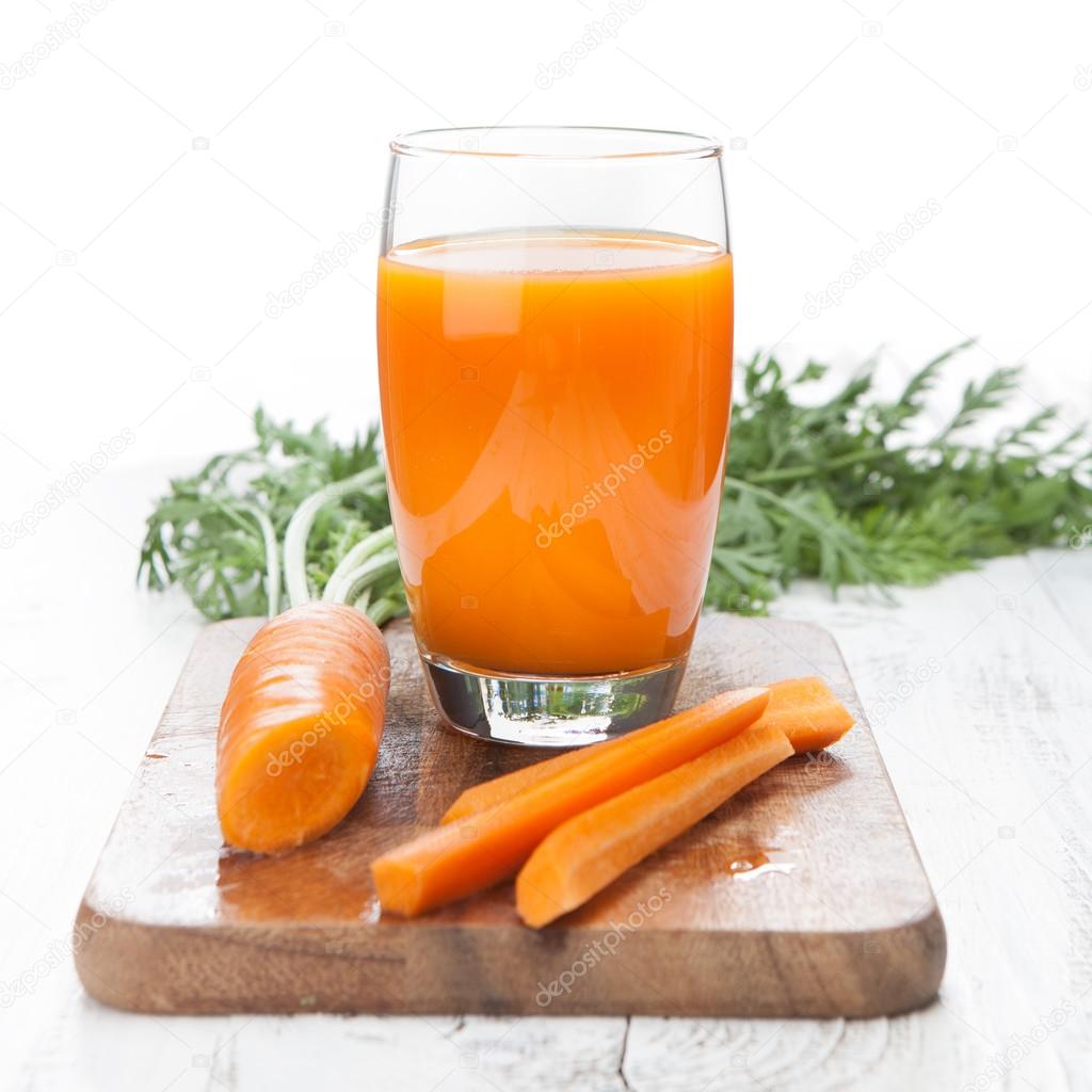 Carrot juice with fresh carrots on white table