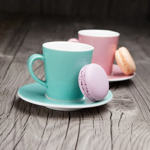 Кофейные чашки с французскими макаронами на столе — стоковое фото