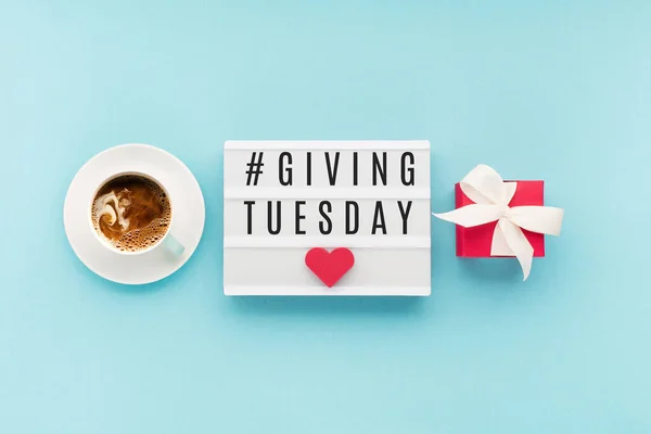 Giving Tuesday, global day of charitable giving after Black Friday shopping day. Charity, give help, donations support concept. Text message, gift box, red hearts and cup of coffee on blue background.