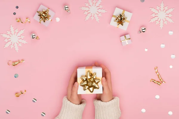 女性の手は 金や銀の装飾 雪の結晶とクリスマスのお祝いのパステルピンクの背景に白いギフトボックスを保持 ホリデークリスマス 新年のコンセプト フラットレイアウト トップビュー コピースペース — ストック写真