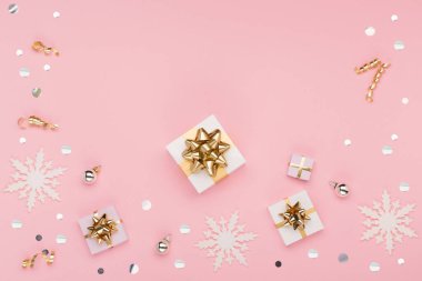 Noel tebrik kartı şablonu. Altın ve gümüş madalyalar, şenlikli hediyeler, pembe arka planda kar taneleri. Xmas, kış, yeni yıl konsepti. Düz konum, üst görünüm, kopyalama alanı.