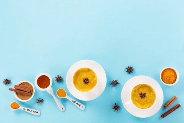 姜黄金牛奶拿铁与香料 肉桂和蜂蜜蓝色背景 免疫增强体质 抗炎健康冬季印度传统饮料 顶部视图 复制空间 — 图库照片