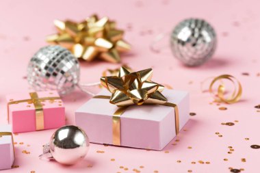 Noel kompozisyonu. Altın ve gümüş süslemeler, ayna disko topları, pastel pembe kağıt arka planda hediyeler. Noel, kış, yeni yıl konsepti. Seçici odak, boşluğu kopyala.