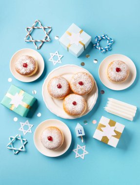 Meyve reçeli, hediye kutuları, kurutulmuş spinnig ve mavi kağıtta mumlar bulunan Hanukkah tatlı donutları sufganiyot (geleneksel çörekler). Yahudi bayramı Hannuka konsepti. Üst görünüm, alanı kopyala.