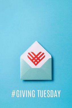 Salı mesajı veriyorum. Kara Cuma alışveriş gününden sonra küresel bağış günü. Bağış, yardım, bağış destek konsepti. Mavi zarf içinde kırmızı kağıt kalp mavi arkaplan, üst görünüm