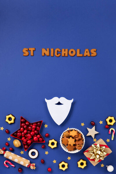 Saint Nicholas Day, 6 December. Christmas composition with sweets, candy, gingerbread cookies and gifts on dark blue background, top view. Traditional winter holiday in Germany and Western Europe.