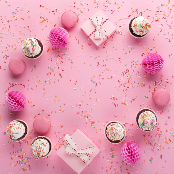 誕生日 女性や母の日のためのお祭りの休日の挨拶カード ピンクの紙の装飾 ピンクのスプリンクルの背景に甘いマカロンとカップケーキ フラットレイアウト トップビュー — ストック写真