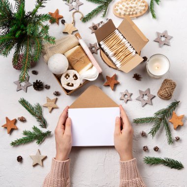 Sıfır atık çevre dostu Noel tatili konsepti. Boş zarf ve Noel için kişisel bakım paketi. İçinde plastiksiz kozmetik ürünleri olan bir hediye kutusu. Beyaz doğal arkaplan, üst görünüm, kopyalama alanı.