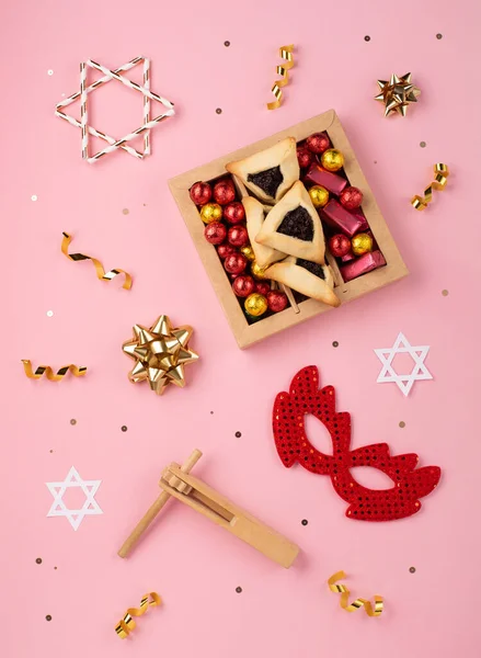 普林庆祝犹太人狂欢节的概念 味道鲜美的哈曼曲奇 红色狂欢节面具 吵闹者 甜糖果和粉色背景的派对装饰 顶视图 复制空间 — 图库照片